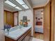 Bathroom with single sink vanity, large mirror and access to bedroom at 1106 Oxbow Rd, Wimauma, FL 33598