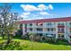 Two-story building with red tile roofs and balconies. Lush landscaping surrounds the property at 1012 Pearce Dr # 209, Clearwater, FL 33764