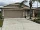 Tan house with two-car garage and landscaping at 6812 Aramon Ct, Wesley Chapel, FL 33545