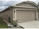Tan two-car garage with landscaping at 6812 Aramon Ct, Wesley Chapel, FL 33545
