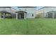 Large backyard with lush green lawn and screened patio at 7779 Yale Harbor Dr, Wesley Chapel, FL 33545