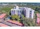 Aerial view of condo building with parking and surrounding trees at 2699 Seville Blvd # 303, Clearwater, FL 33764