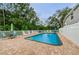 Inviting backyard pool area featuring a brick patio, white fencing, and comfortable lounge chairs for relaxing poolside at 4399 Brooker Creek Dr, Palm Harbor, FL 34685