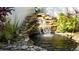 Serene backyard waterfall feature with lush landscaping at 1214 Bolivar Ct, Dunedin, FL 34698