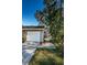 Tan house with white garage door and walkway, surrounded by trees at 4399 Brooker Creek Dr, Palm Harbor, FL 34685