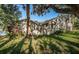 Side view of tan house with green lawn and large trees at 4399 Brooker Creek Dr, Palm Harbor, FL 34685