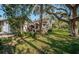 Back exterior of house nestled among large trees with green grass at 4399 Brooker Creek Dr, Palm Harbor, FL 34685