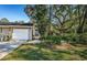 Tan house with white garage door and walkway, surrounded by lush landscaping at 4399 Brooker Creek Dr, Palm Harbor, FL 34685
