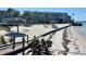 Scenic view of the community beach with tiki umbrellas and lounge chairs, framed by clear blue water and lush foliage at 6061 Bahia Del Mar Cir # 241, St Petersburg, FL 33715
