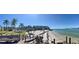 Expansive beach view showcasing lounge chairs and tiki umbrellas, backed by lush palms and waterfront condo buildings at 6061 Bahia Del Mar Cir # 241, St Petersburg, FL 33715