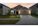 Two-car garage and front yard view of house exterior at dusk at 15502 Black Pepper Ln, Odessa, FL 33556