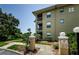 Multi-story tan condo building with balconies, surrounded by lush green landscaping and a clear blue sky at 2690 Coral Landings Blvd # 722, Palm Harbor, FL 34684