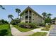 Exterior of a multi-story condo building with balconies, green lawns, mature palm trees, and clear blue skies at 2690 Coral Landings Blvd # 722, Palm Harbor, FL 34684