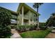 Condo building's exterior featuring balconies, green lawn, mature trees, and a clear blue sky at 2690 Coral Landings Blvd # 722, Palm Harbor, FL 34684