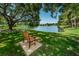Tranquil lake view with a wooden bench under a large tree, perfect for relaxation at 2690 Coral Landings Blvd # 722, Palm Harbor, FL 34684