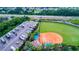 Aerial view of community amenities, including RV parking, a baseball field, a pond, and lush green spaces at 4847 Marble Springs Cir, Wimauma, FL 33598