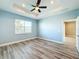 Light-filled bedroom with wood flooring, tray ceiling, ceiling fan, and an ensuite bathroom at 4847 Marble Springs Cir, Wimauma, FL 33598