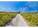 Gravel road lined with chain link fence and vegetation at 1810 Curry Rd, Lutz, FL 33549