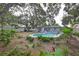 Lush backyard with mature trees, an in-ground pool and tropical landscaping at 664 Frederica Ln, Dunedin, FL 34698