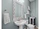 Elegant powder room featuring a pedestal sink, ornate mirror, and decorative shelving, exuding a refined charm at 4915 Augusta Ave, Oldsmar, FL 34677