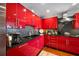 Modern red kitchen with black countertops and stainless steel appliances at 1 Beach Se Dr # 2007, St Petersburg, FL 33701