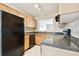 A galley-style kitchen with wood cabinets, black appliances, and granite countertops at 3825 Pompano Se Dr, St Petersburg, FL 33705