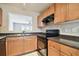 L-shaped kitchen with wood cabinets, black appliances, and granite countertops at 3825 Pompano Se Dr, St Petersburg, FL 33705