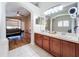 Double vanity bathroom with wood cabinets and view into bedroom at 4630 Pointe O Woods Dr, Wesley Chapel, FL 33543