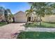 Tan house with brick driveway, palm trees, and manicured landscaping at 1804 Pacific Dunes Dr, Sun City Center, FL 33573