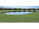 Serene community pond with grassy areas and houses reflecting on the water at 1804 Pacific Dunes Dr, Sun City Center, FL 33573