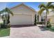 Tan house with brick driveway, palm trees, and manicured landscaping at 1804 Pacific Dunes Dr, Sun City Center, FL 33573