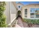 Brick walkway to entryway of tan house with dark door and wreath at 1804 Pacific Dunes Dr, Sun City Center, FL 33573