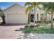 Tan house with brick driveway, palm trees, and manicured landscaping at 1804 Pacific Dunes Dr, Sun City Center, FL 33573