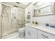 Bright bathroom with white vanity, tiled shower with glass doors, white tile floors, and a framed mirror at 2390 Shelly Dr # D, Palm Harbor, FL 34684