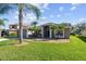 Charming home with mature palm trees, a well-manicured lawn, and a neutral-toned facade, all under a sunny sky at 4538 Pointe O Woods Dr, Wesley Chapel, FL 33543