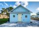 Light blue house with a yellow door, stone patio, and landscaping at 509 W Cedar St, Tarpon Springs, FL 34689