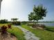 Tranquil backyard landscaping featuring stone pathway, flowers, trees, and a scenic lake backdrop at 1027 Ocean Spray Dr, Ruskin, FL 33570