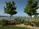 Waterfront landscaping featuring beautiful flowers, decorative rocks and mature trees at 1027 Ocean Spray Dr, Ruskin, FL 33570