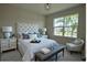Tastefully decorated bedroom with a luxurious upholstered headboard, bench and a large window at 1027 Ocean Spray Dr, Ruskin, FL 33570