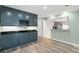 Kitchen with blue cabinets, wine rack, subway tile, black countertops, and wood grain floors at 104 Cypress Pond Rd, Palm Harbor, FL 34683