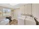 Bright laundry room with tile floors, washer, dryer, storage cabinets, and a view to the green outdoors at 2104 Hembury Pl # 33, Sun City Center, FL 33573