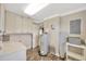 Laundry room with washer, dryer, water heater, cabinets, and an ironing board at 2104 Hembury Pl # 33, Sun City Center, FL 33573