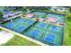 An aerial view featuring multiple pickleball courts, surrounded by lush greenery, and shaded seating for players at 2104 Hembury Pl # 33, Sun City Center, FL 33573