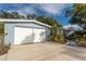 Light blue home featuring a white two car garage, concrete driveway and meticulously kept landscaping at 351 Barbara Cir, Belleair, FL 33756