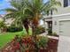 Landscaped front yard with palm trees and colorful flowers at 7672 Tuscan Bay Cir, Wesley Chapel, FL 33545