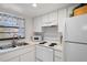 Bright kitchen featuring white cabinets, appliances, and a window with decorative curtains, a functional and inviting space at 2571 Cyprus Dr # 1-202, Palm Harbor, FL 34684