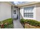Inviting front entry with ramp access, storm door, and well-manicured landscaping at 4234 Chesterfield Cir, Palm Harbor, FL 34683