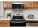 Close up of kitchen featuring stainless steel range, oven, microwave, and white backsplash at 5721 12Th S Ave, Gulfport, FL 33707