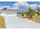 Charming single-story home featuring a well-manicured lawn, driveway, and attached garage under a sunny sky at 907 La Jolla Ave, Sun City Center, FL 33573