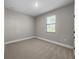 Well-lit bedroom featuring a window with blinds and neutral-toned carpet at 12152 Snow Bird Ave, Port Charlotte, FL 33981